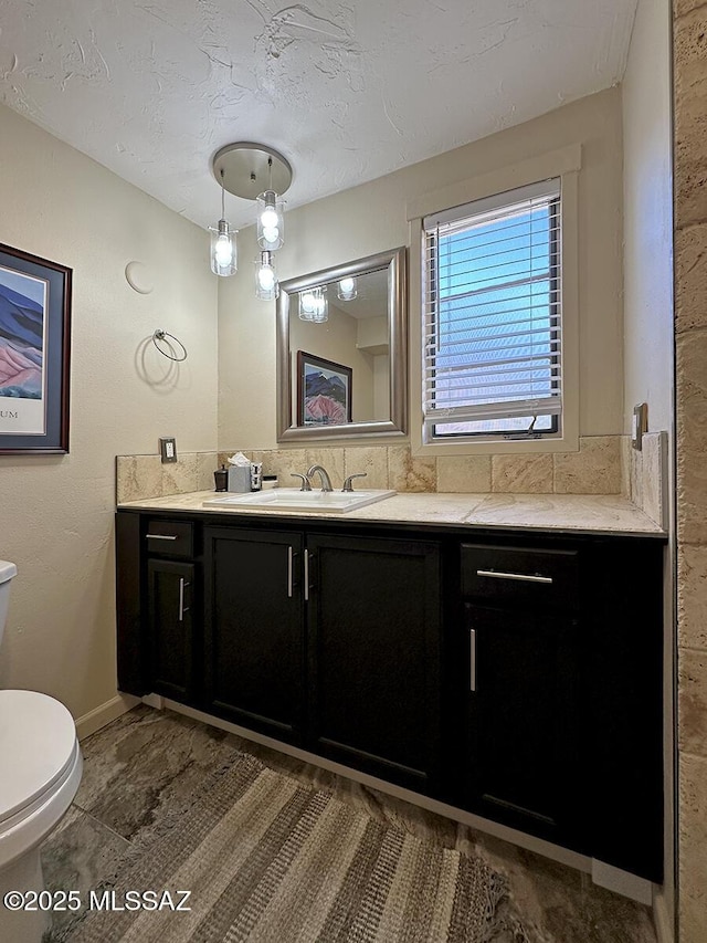 bathroom with toilet, a textured ceiling, and vanity