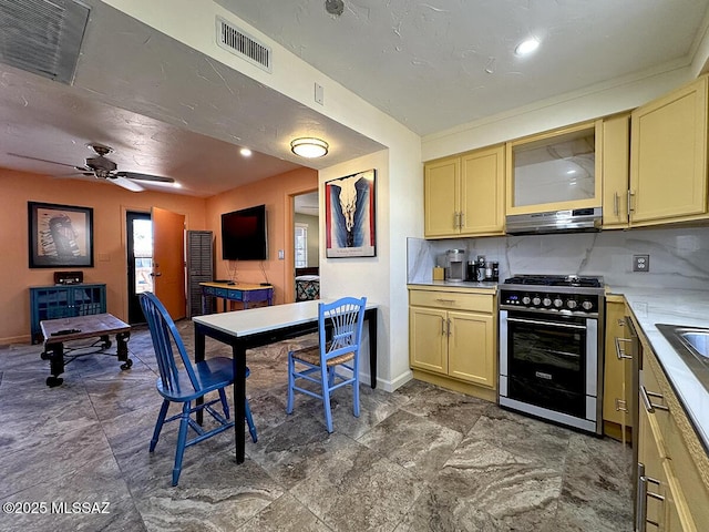 kitchen featuring ceiling fan, decorative backsplash, high end stainless steel range, and light brown cabinetry