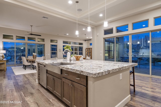 kitchen with hardwood / wood-style floors, sink, hanging light fixtures, a kitchen island with sink, and ceiling fan