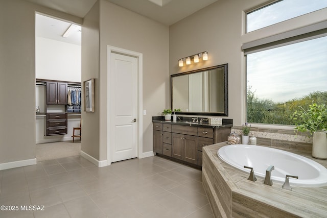 bathroom featuring tile patterned flooring, vanity, and tiled tub