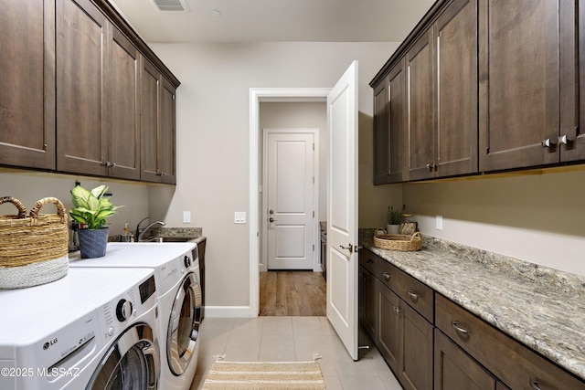 washroom with cabinets, sink, washing machine and dryer, and light tile patterned floors