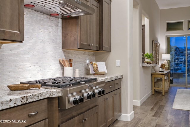 kitchen with light stone counters, tasteful backsplash, stainless steel gas stovetop, and custom range hood