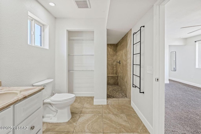 bathroom with toilet, tiled shower, tile patterned floors, vanity, and ceiling fan