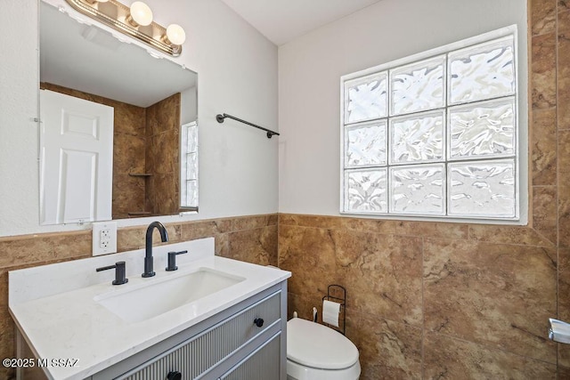 bathroom featuring toilet, vanity, and tile walls