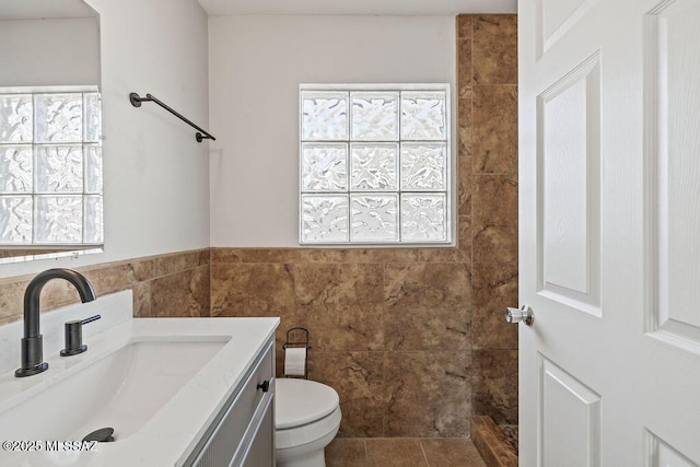 bathroom featuring tile walls, toilet, a wealth of natural light, and vanity