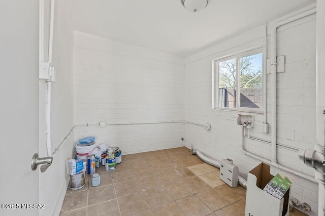 laundry area featuring brick wall