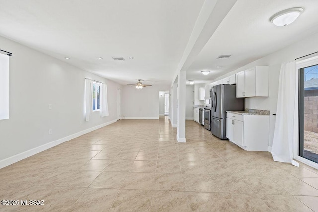 kitchen featuring stainless steel refrigerator, ceiling fan, a wealth of natural light, and white cabinetry