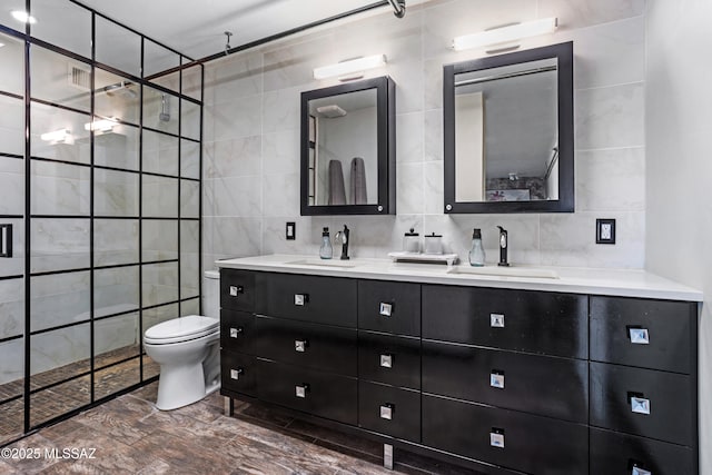 bathroom with toilet, a tile shower, tile walls, and vanity