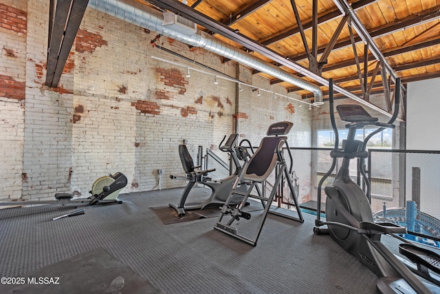 gym featuring high vaulted ceiling and brick wall