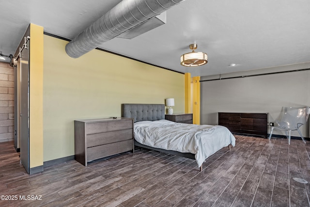 bedroom featuring dark hardwood / wood-style floors and a barn door