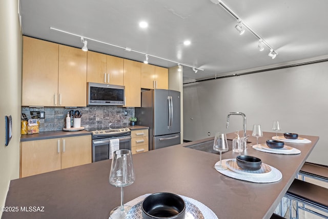 kitchen with light brown cabinetry, stainless steel appliances, decorative backsplash, and rail lighting