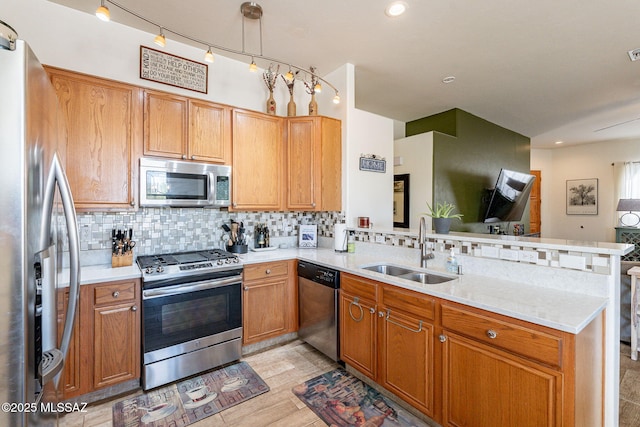 kitchen with sink, stainless steel appliances, decorative backsplash, decorative light fixtures, and kitchen peninsula