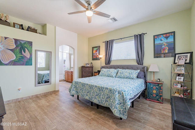 bedroom featuring multiple windows, light hardwood / wood-style flooring, ceiling fan, and ensuite bath