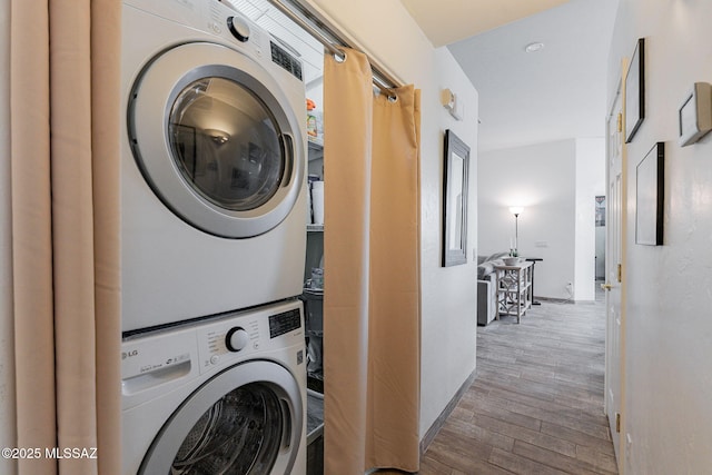 washroom featuring stacked washing maching and dryer and light wood-type flooring