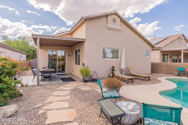 rear view of house with a fenced in pool and a patio area