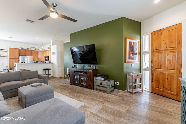 living room with ceiling fan and light hardwood / wood-style flooring