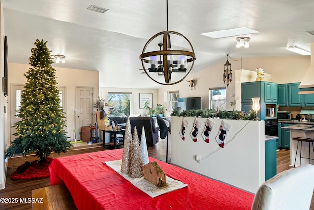 dining area with an inviting chandelier, hardwood / wood-style flooring, and vaulted ceiling with skylight