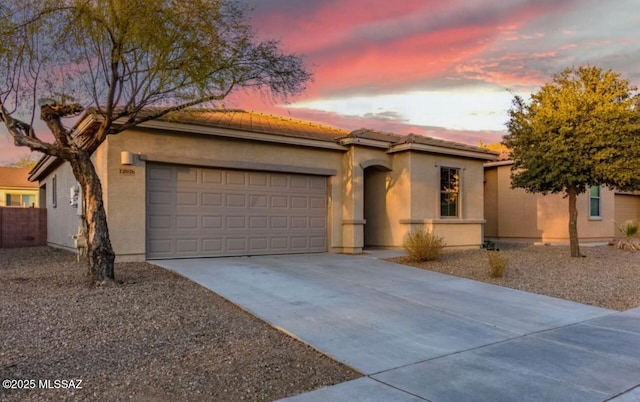 view of front of house featuring a tile roof, driveway, an attached garage, and stucco siding