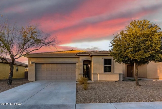 view of front of home featuring concrete driveway, a tiled roof, an attached garage, and stucco siding