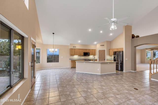 kitchen with pendant lighting, sink, stainless steel fridge, an island with sink, and ceiling fan with notable chandelier