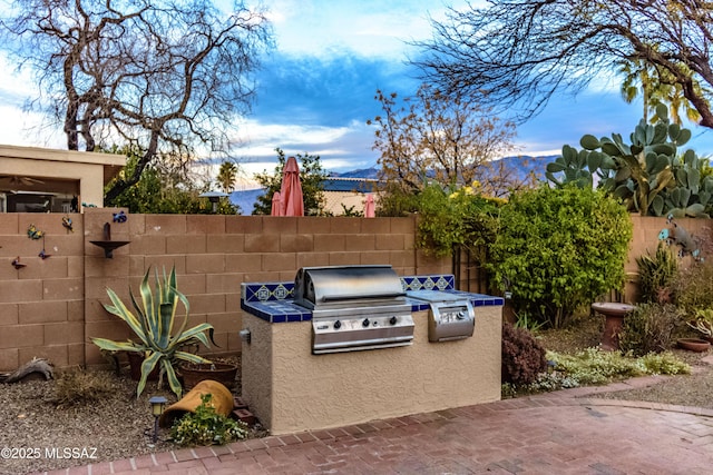 view of patio featuring area for grilling, a mountain view, and an outdoor kitchen