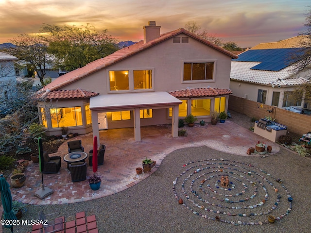 back house at dusk featuring a patio