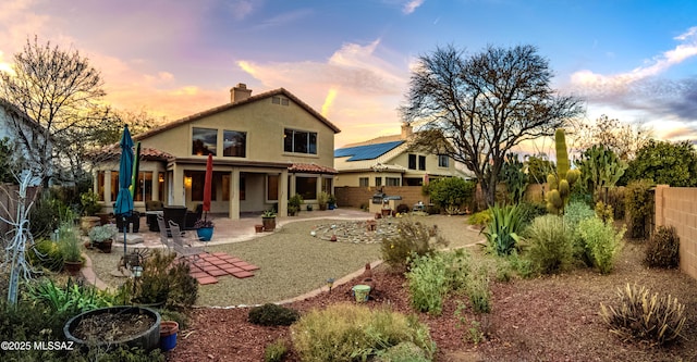 back house at dusk featuring a patio