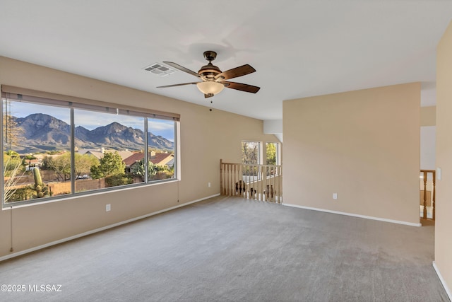 carpeted empty room featuring a mountain view and ceiling fan