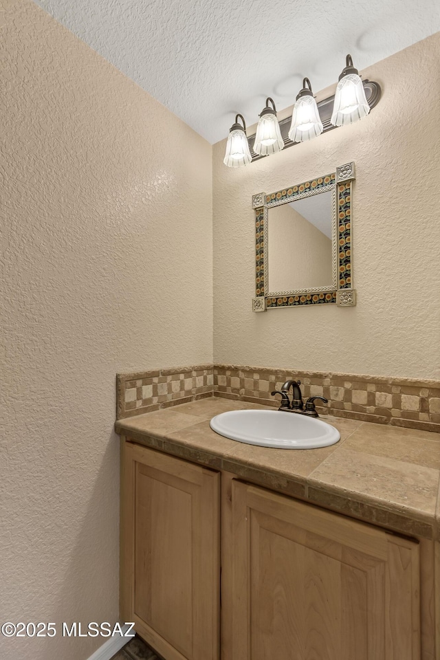 bathroom featuring decorative backsplash, vanity, and a textured ceiling