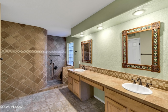 bathroom with vanity, tile patterned flooring, decorative backsplash, and tiled shower