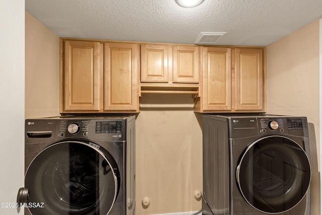 washroom with washer / clothes dryer, a textured ceiling, and cabinets