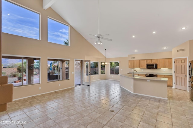 kitchen with appliances with stainless steel finishes, ceiling fan with notable chandelier, an island with sink, sink, and light brown cabinets