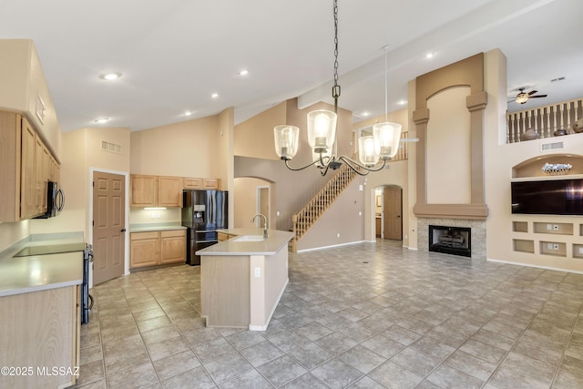 kitchen featuring sink, a tile fireplace, hanging light fixtures, fridge with ice dispenser, and light brown cabinetry