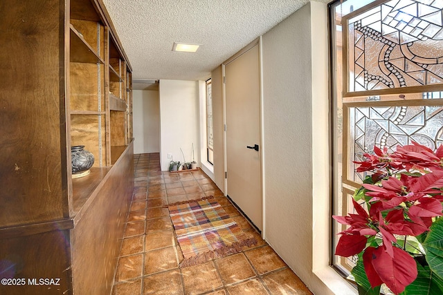 corridor featuring tile patterned flooring and a textured ceiling