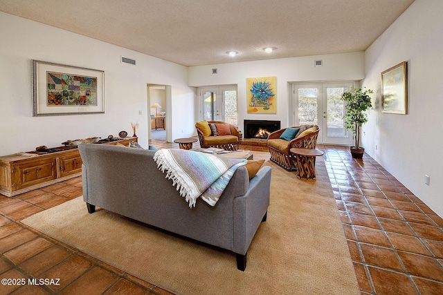 living room with tile patterned flooring, a brick fireplace, french doors, and a textured ceiling