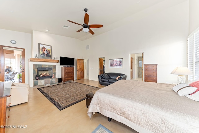 bedroom with ceiling fan, high vaulted ceiling, ensuite bath, and a tiled fireplace