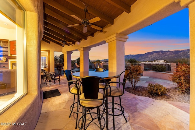 patio terrace at dusk with ceiling fan and a mountain view