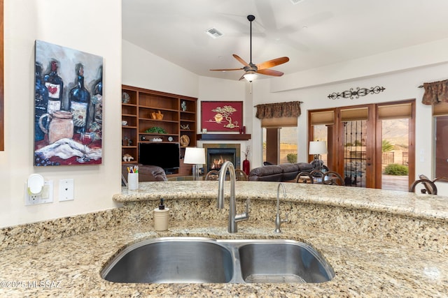 kitchen with light stone countertops, ceiling fan, plenty of natural light, and sink