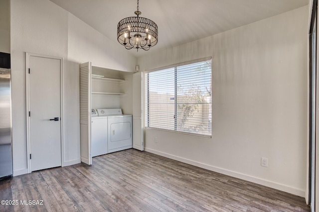 laundry room with washing machine and dryer, an inviting chandelier, and light wood-type flooring