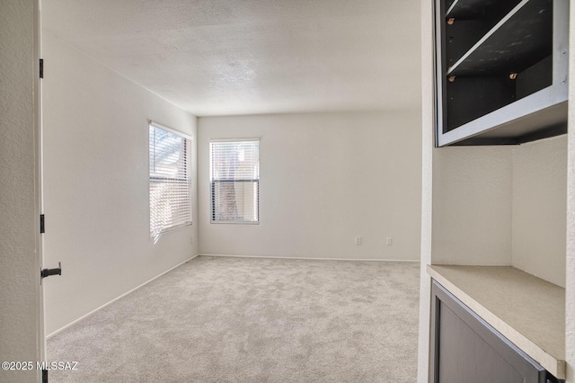 empty room with a textured ceiling and light carpet