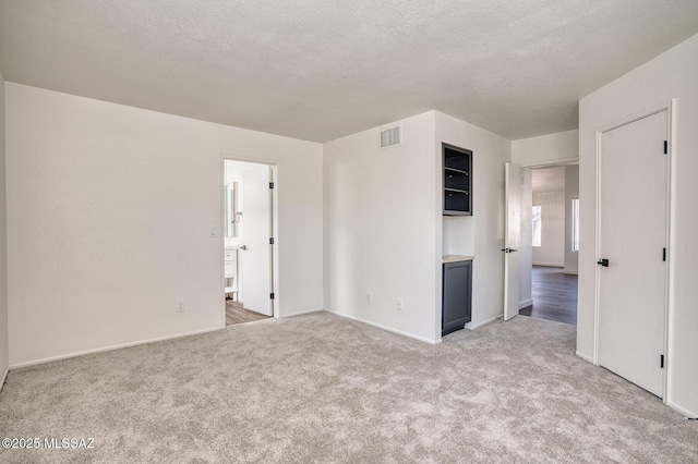 unfurnished room with light colored carpet and a textured ceiling