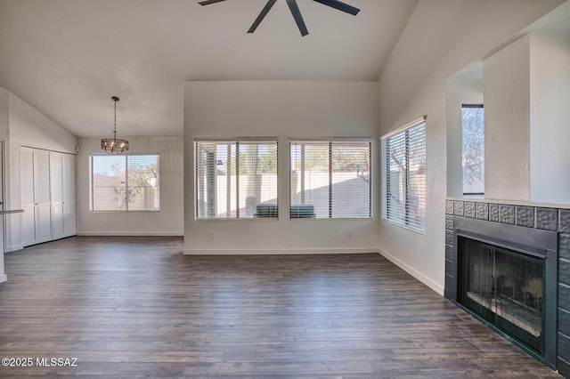 unfurnished living room with lofted ceiling, a fireplace, dark hardwood / wood-style flooring, and ceiling fan with notable chandelier