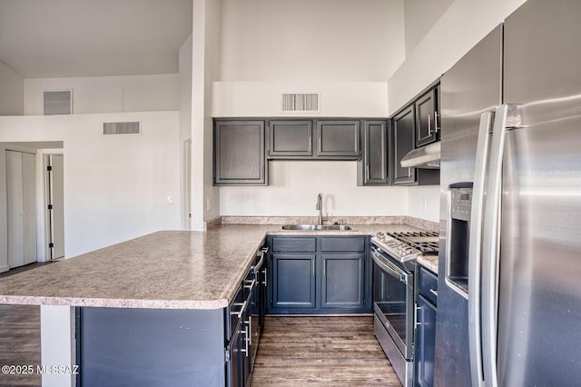 kitchen featuring stainless steel appliances, sink, kitchen peninsula, and dark wood-type flooring