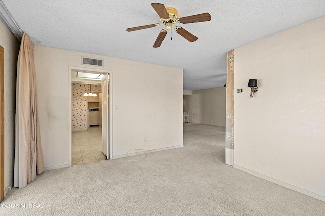 empty room with ceiling fan, light colored carpet, and a textured ceiling