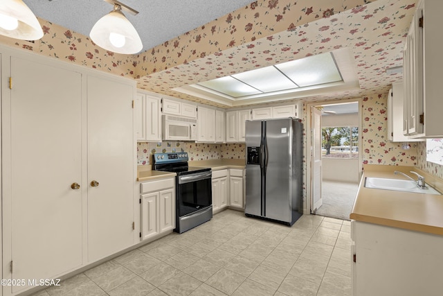 kitchen featuring sink, a raised ceiling, white cabinets, and appliances with stainless steel finishes