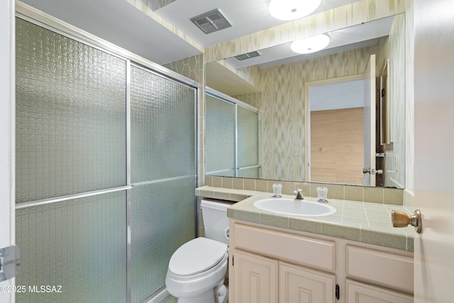 bathroom with toilet, vanity, and an enclosed shower