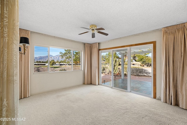 carpeted empty room featuring a mountain view, a textured ceiling, and ceiling fan