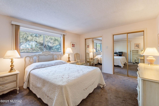 carpeted bedroom with a textured ceiling and two closets