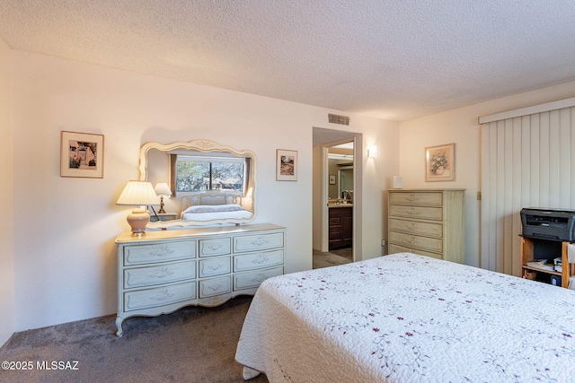 carpeted bedroom with a textured ceiling and ensuite bathroom