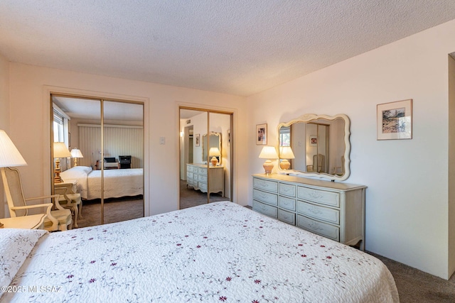 bedroom with a textured ceiling, two closets, and dark carpet